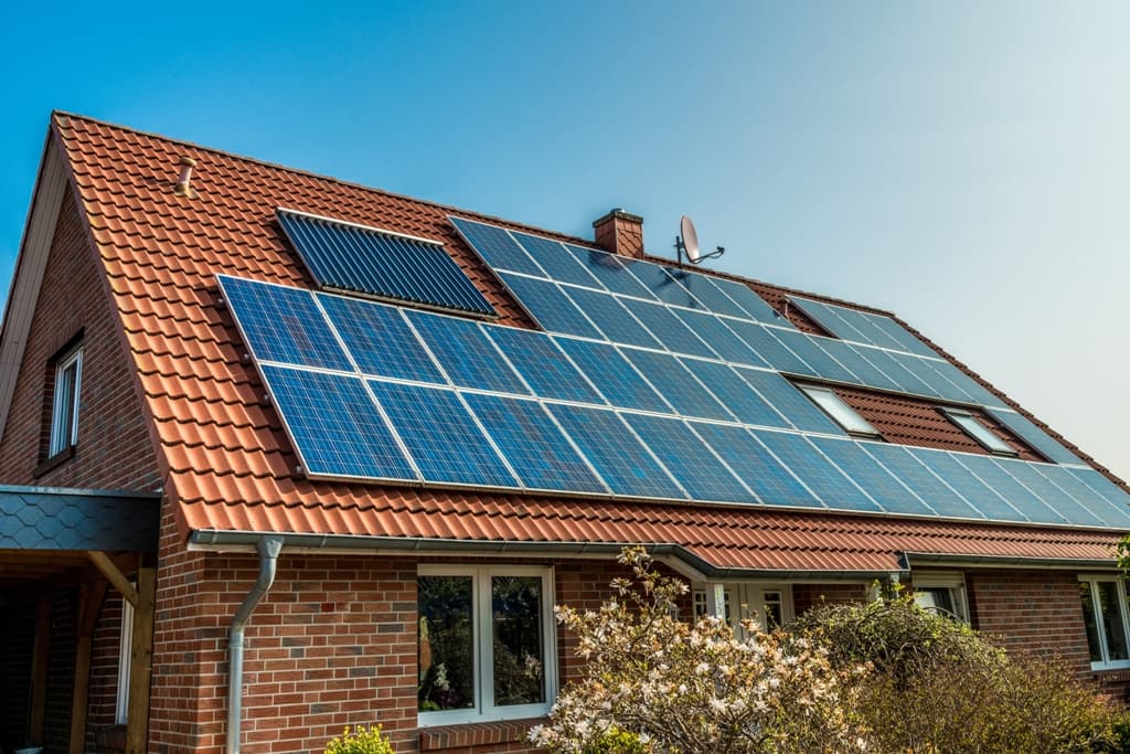 Casa com painéis solares no telhado ilustra post sobre aquecimento solar da água
