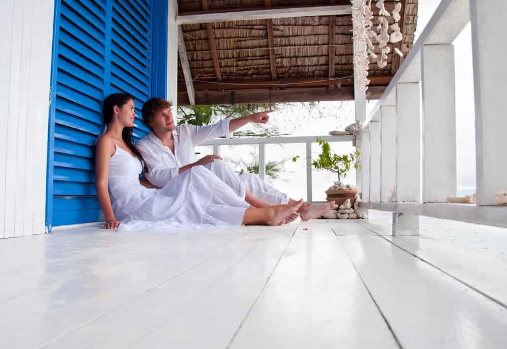 Casal descansando e relaxa em casa de praia ilustra post sobre vantagens de ter uma casa de praia