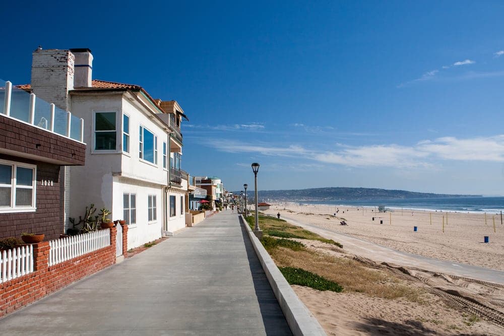 Imagem mostra casas à beira da praia e ilustra post sobre vantagens de ter uma casa na praia da loteadora Soma Urbanismo