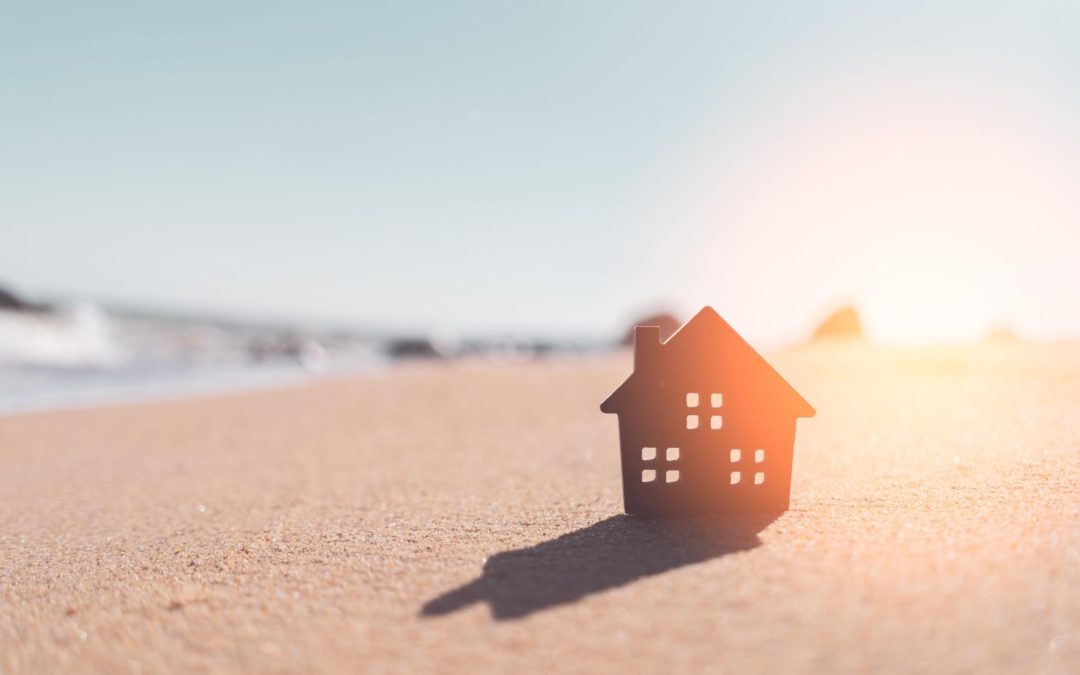 Casa de madeira na areia na praia. Imagem ilustrativa para post sobre vantagens de ter uma casa na praia, do blog da Soma Urbanismo.