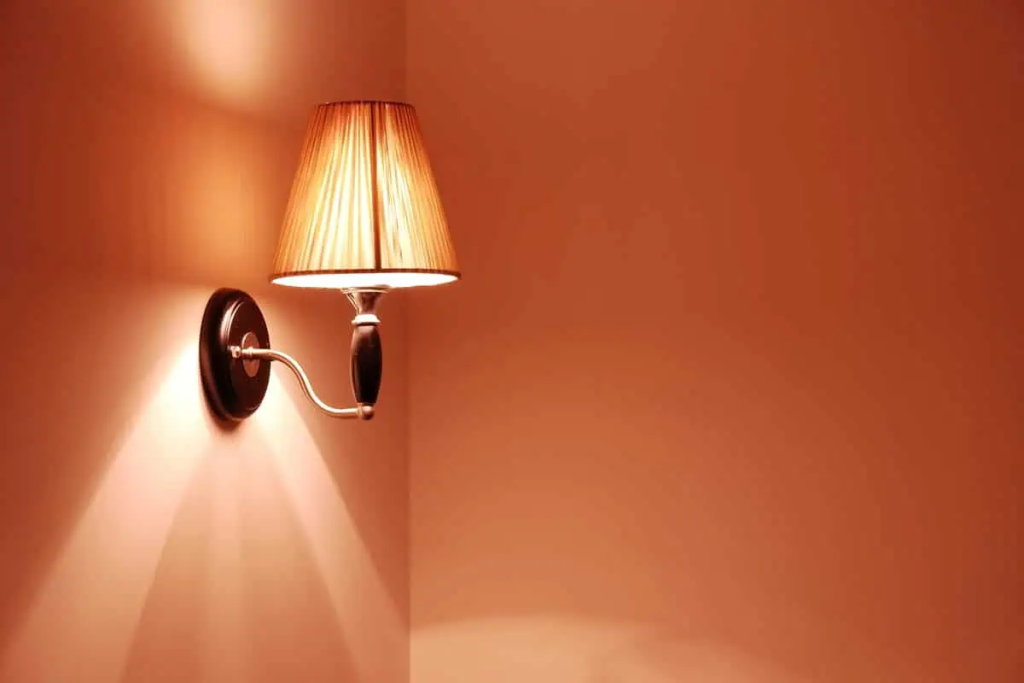 Arandela acesa projetando luz quente na parede, criando um ambiente acolhedor. Imagem ilustrativa para post sobre como deixar a casa mais quentinha no inverno, do blog da Soma Urbanismo.