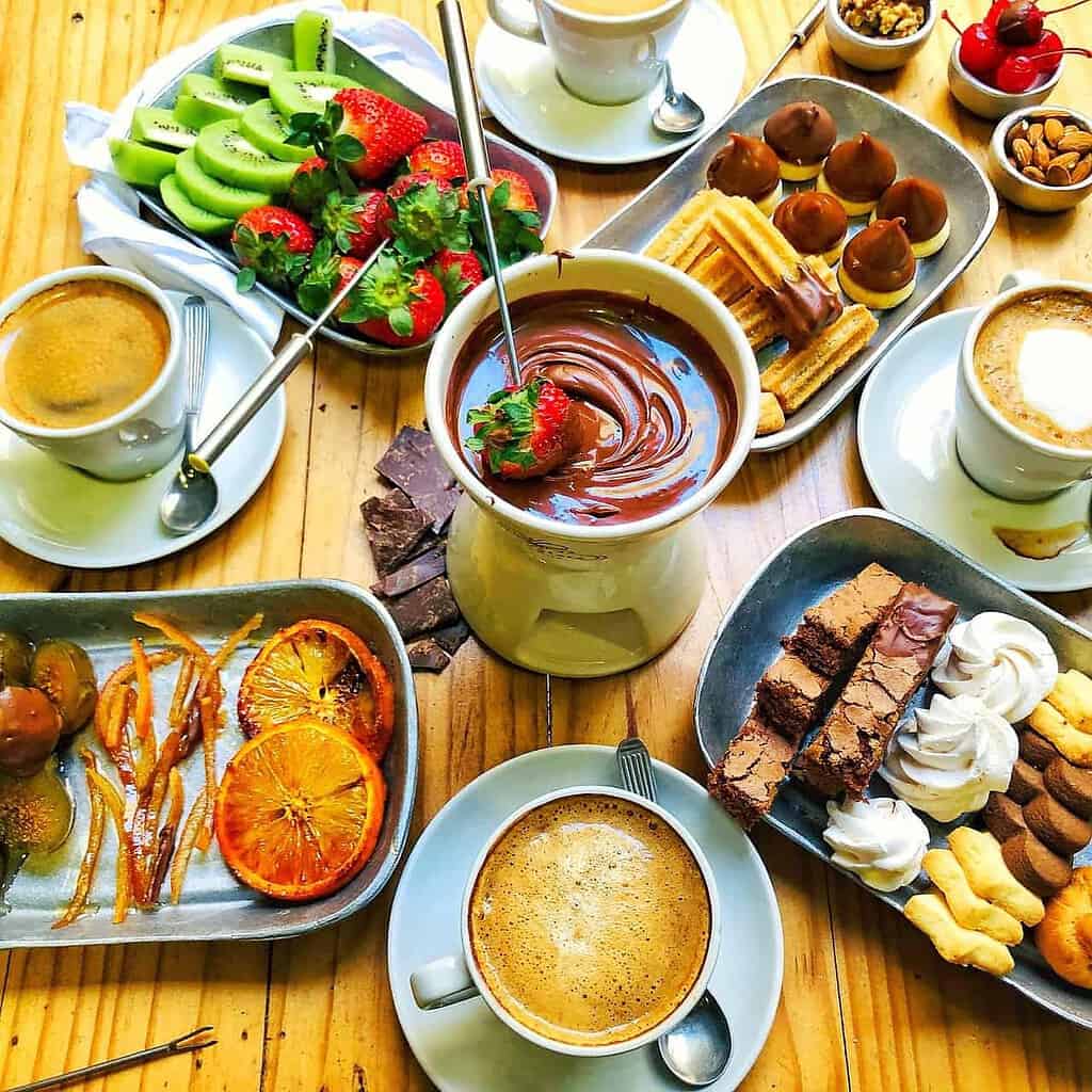 Foto de uma mesa com fondue, frutas e doces para ilustrar o texto sobre o que fazer no inverno do blog da Soma Urbanismo.