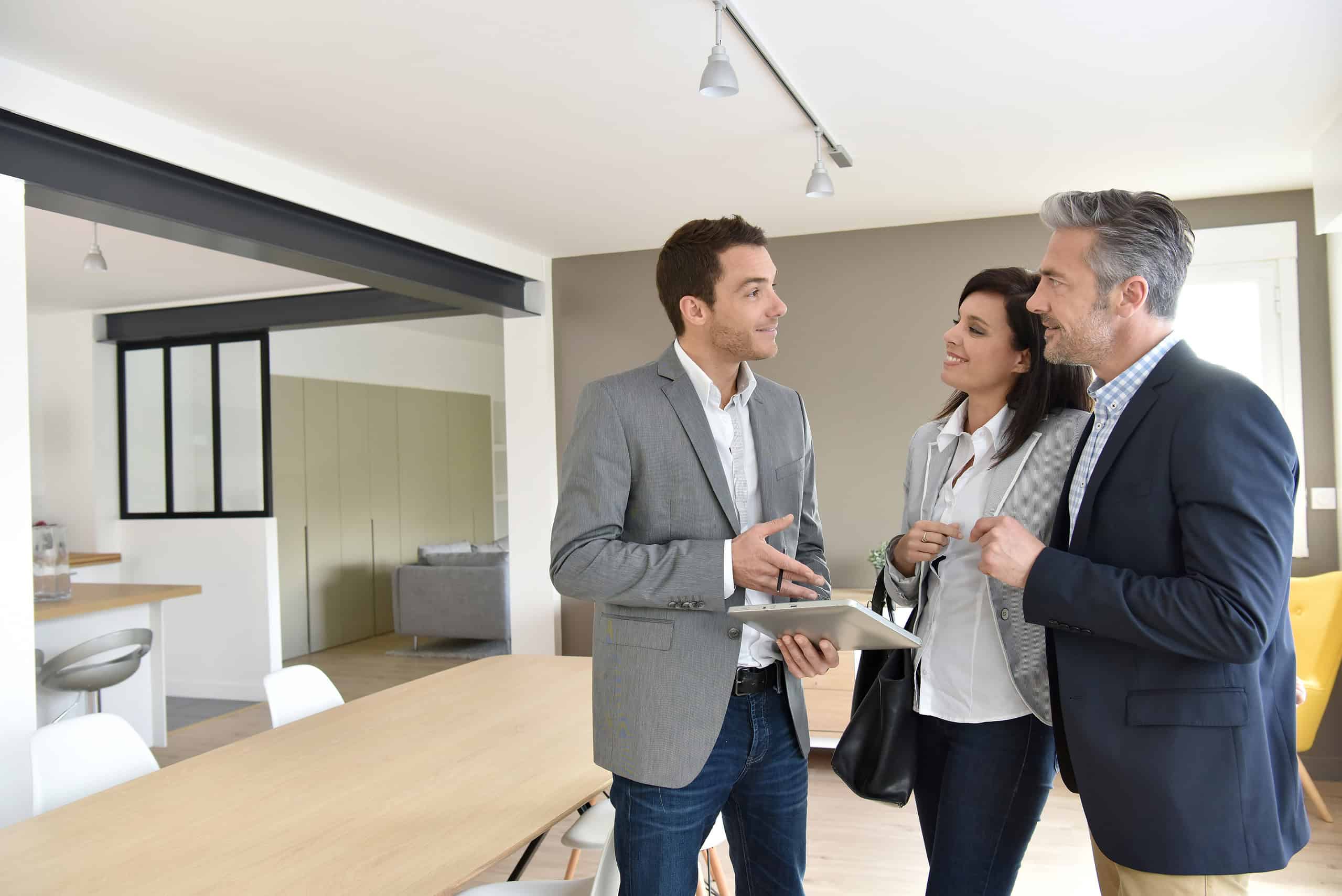 Foto de um casal conversando com um corretor em uma sala planejada para ilustrar o texto sobre como convencer um cliente a comprar um lote da Soma Urbanismo.