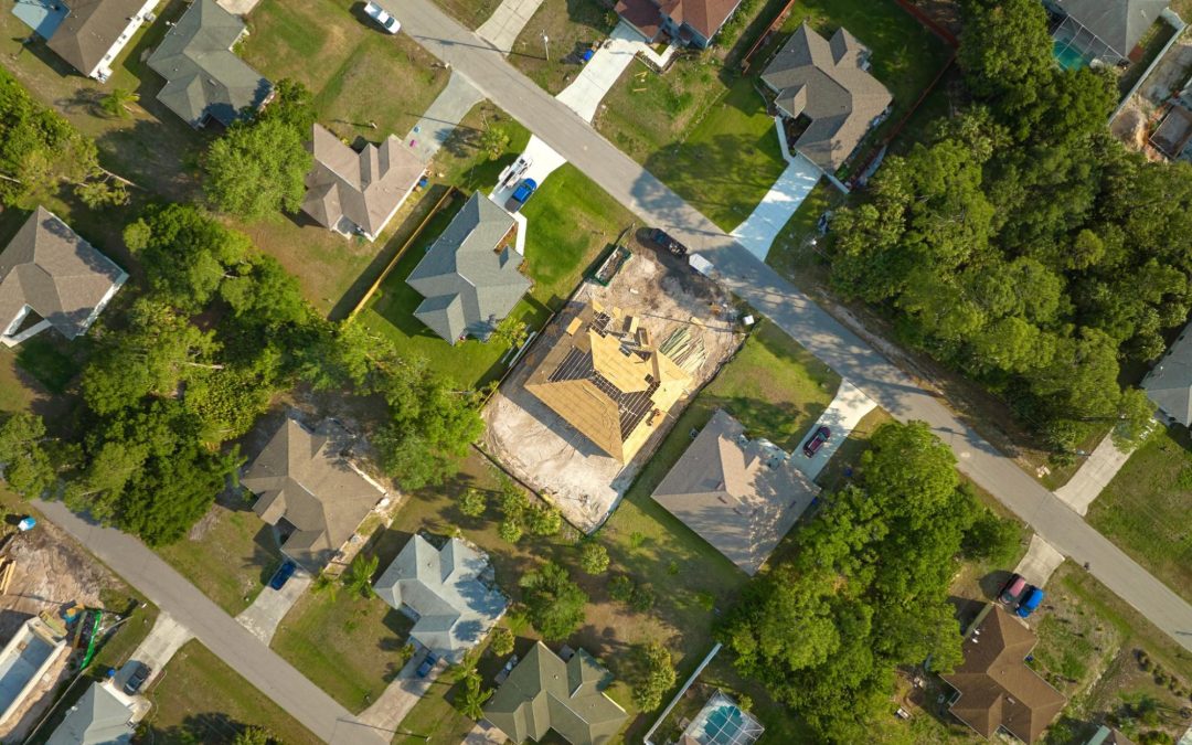 Imagem aérea de casas em meio a árvores. Imagem ilustrativa para post que fala sobre as diferenças entre imóveis rurais e urbanos.