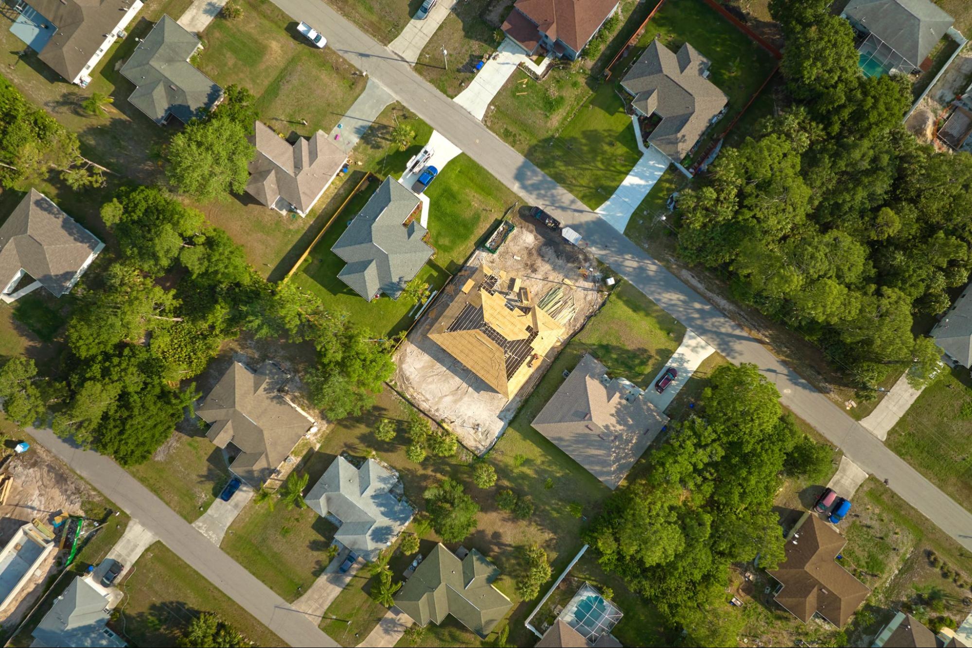 Imagem aérea de casas em meio a árvores. Imagem ilustrativa para post que fala sobre as diferenças entre imóveis rurais e urbanos.