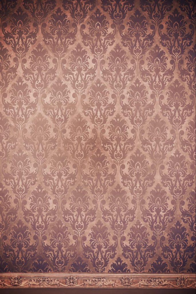 Papel de parede vintage com estampa clássica em tons terrosos e detalhes em dourado.