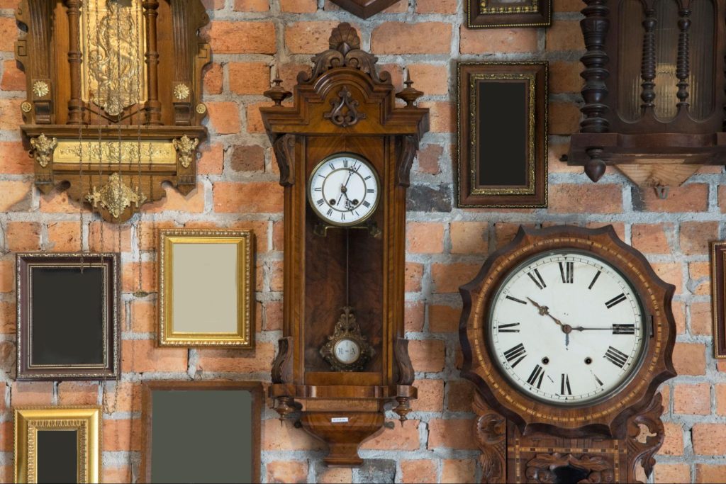 Parede de tijolos com relógios antigos de madeira e molduras vazias, estilo vintage.