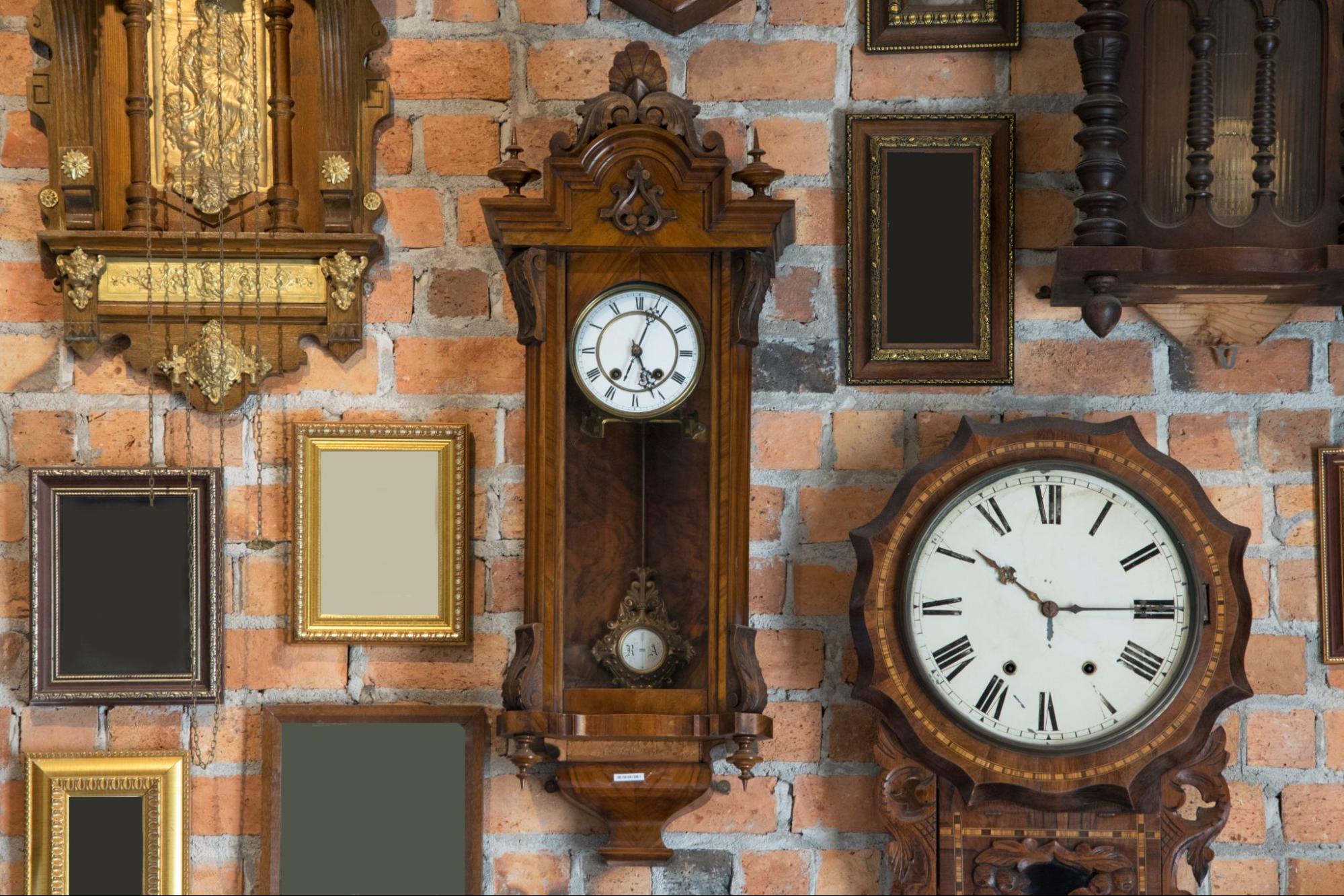 Parede de tijolos com relógios antigos de madeira e molduras vazias, estilo vintage.
