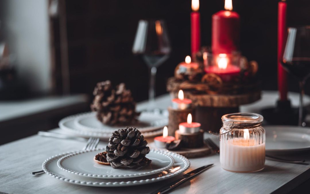 Mesa com velas, pratos e pinhas ilustra post sobre decoração de Ano Novo, para o blog da Soma Urbanismo.
