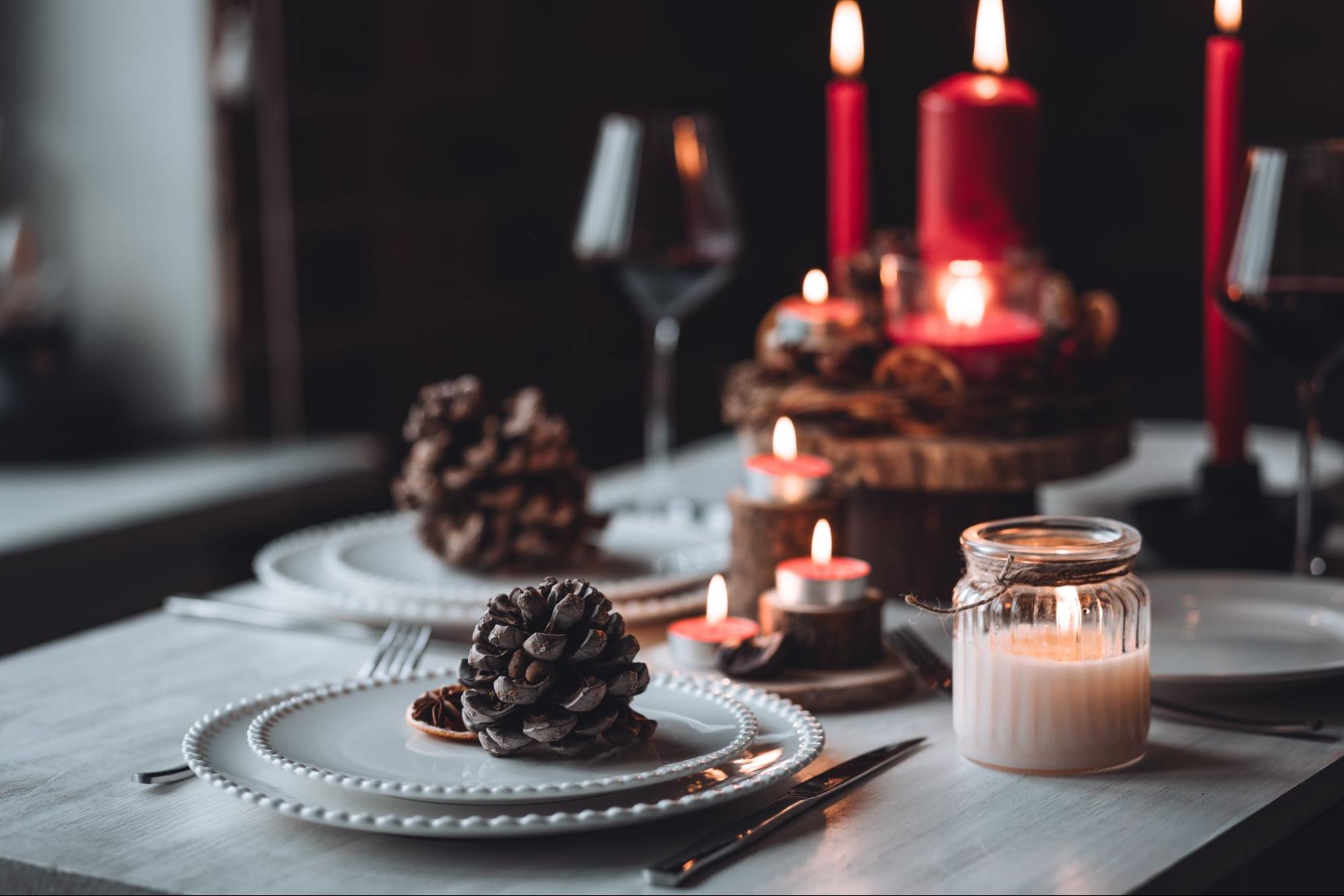 Mesa com velas, pratos e pinhas ilustra post sobre decoração de Ano Novo, para o blog da Soma Urbanismo.